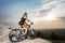 Woman with the mountain bike under a sky at sunset