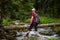 a woman on a mountain hike stops by a stream and looks where to go next