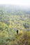 A woman on the mountain side looking at the forest of endless autumn taiga