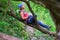 Woman mountaineer with a blue helmet resting on a tree branch, in Tureni-Copaceni gorge, Romania.