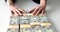 Woman moves away stacks of dollar banknotes on white table