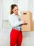 Woman moving into apartment house carrying boxes.