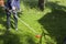 Woman mowing green grass with hand trimmer