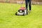 a woman mows her green lawn in summer