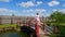 Woman in national dress goes with a basket on the bridge across the pond.