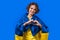 Woman with national Ukrainian flag showing sign of shape heart on yellow.Volunteering, charity donation, gratitude