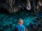 Woman in natural lake inside cave. Colorful reflection, turquoise transparent water, summer adventures. Tourist destination, Kei