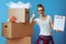 Woman near cardboard box showing moving checklist and thumbs up