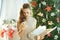 Woman near Christmas tree looking at broken dish from parcel