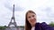 Woman near Eiffel Tower using mobile talking via messenger app. Smiling tourist woman traveling in Europe.