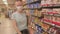 Woman near goods on the shelf. Choice of sweets.