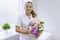 Woman nurse with bouquet of flowers, smiling near the window in the hospital. National Doctor`s day