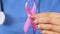 Woman nurse holding pink ribbon, international symbol of breast cancer awareness