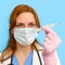 Woman nurse with a thermometer on a blue background, face closeup