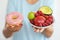 Woman offering different alternative of food, fresh fruits and unhealthy donut