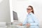 Woman in office at desk in front of computer, mouse click