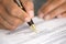 Woman at office desk signing a contract with shallow focus on si