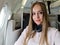 woman in official clothes wears headphones, businesswoman sitting in business premium class cabin on aircraft