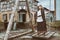 A woman in old-fashioned clothes stands on a vintage swing. Street of the old city with houses in the style of 18-19 centuries and