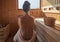 Woman with open back relaxing in the wellness spa, sweating in Finnish sauna