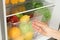 Woman opening refrigerator drawer with fresh fruits