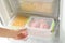 Woman opening refrigerator drawer with frozen products