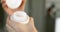 Woman is opening white plastic jar and using cream, hands close-up.