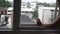 Woman opening window after rain, city houses background