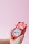 Woman opens a gift box with jewellery. Wedding ring in a box in the hands of women on a pink background