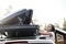 Woman opens the trunk or cargo box, which is located on the roof of the car. Preparing for a vacation.