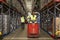 Woman operating tow tractor in a busy distribution warehouse