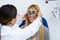 Woman optometrist with trial frame checking patient`s vision at eye clinic.