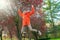 Woman in orange coat jumping in park