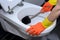 Woman in orange gloves cleaning the toilet