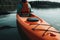 A woman in a orange kayak is sitting in a lake. AI generation