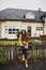 Woman in orange sweater and boots sitting on fence of scandinavian house