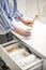 Woman organizing environmental bathroom amenities in drawer and putting bamboo toothbrush into a cup