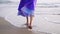 A woman in an oriental dress is walking along the seashore. Legs close up