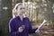 Woman Orienteering In Woodlands With Map And Compass