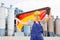 woman in overalls with Germany flag in her hands against the background of chimneys of modern factory