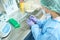 Woman in overalls and protective gloves marks test tubes with biomaterial