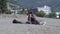 Woman owner hugs small Dachshund dog on sand beach by hotel