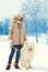 Woman owner and white Samoyed dog on leash walking in winter