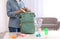 Woman packing baby accessories into maternity backpack on table indoors