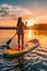Woman on a paddleboard in a calm lake during sunrise