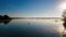 Woman paddling on SUP board on beautiful lake during sunset or sunrise, standing up paddle boarding