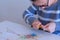 Woman painter in glasses sharpening pencil using sharp knife in art studio.