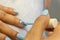 A woman painting her nails on a finger with a blue polish bottle and legs background