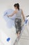 Woman Painting Wall With Paintroller While Standing On Stepladder
