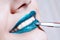 Woman paints her lips with glossy blue lipstick